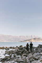 guy and girl are walking along the sunny beach holding hand