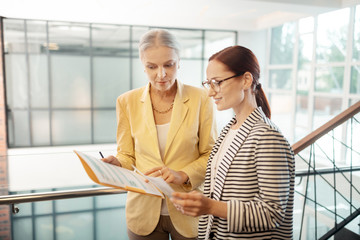 Young red-haired smiling female entrepreneur looking at documents