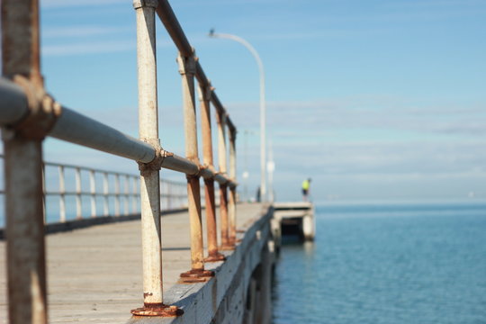 lone man standing on an old timber jetty hobby fishing on a sunny afternoon on the coast, Melbourne, Victoria, Australia © fieldofvision