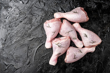 Raw chicken legs on black background.