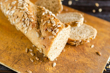 Sliced freshly baked bread on on cutting board. Kitchen utensils, organic food.