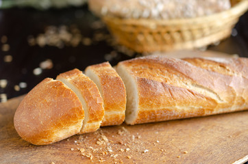 Sliced freshly baked bread on on cutting board. Kitchen utensils, organic food.