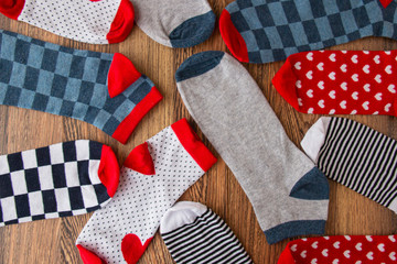 Multi-colored socks on a wooden background. View from above. Many different socks for the cold season. Socks are scattered on a bright background. Clothes in the form of socks.
