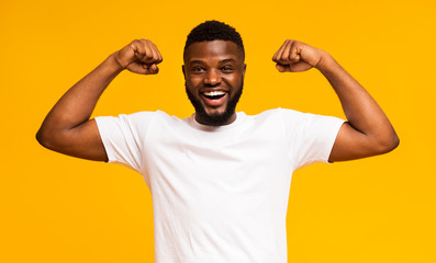 African american man smiling and showing biceps at camera - Powered by Adobe
