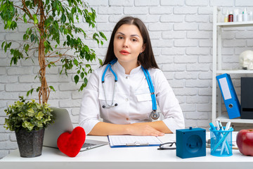 Young female doctor cardiologist sitting at her desk and working