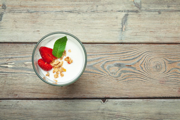 glass of healthy strawberry yogurt with fresh berries on wooden table top view
