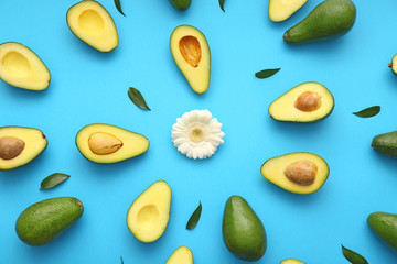 Fresh avocados and flower on color background