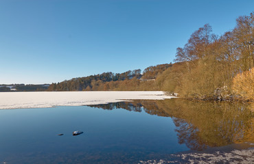 Surface Ice melting at the edges of Loch Clunie in Forneth near Blairgowrie in Perthshire on one Winters evening in January. Scotland.