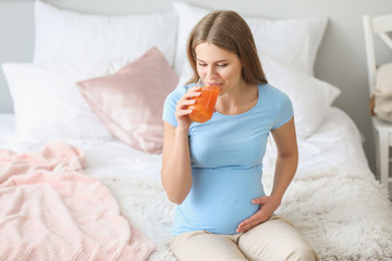 Obraz na płótnie Canvas Beautiful pregnant woman drinking juice at home