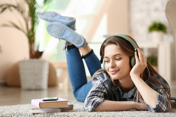 Beautiful young woman listening to audiobook at home