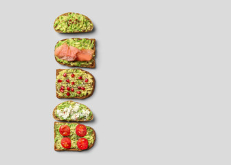 Different tasty avocado toasts on grey background