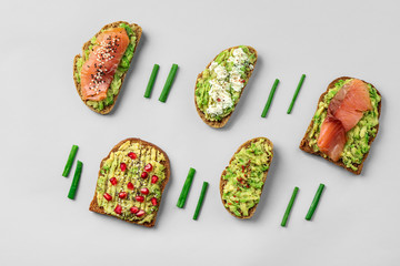 Different tasty avocado toasts on grey background