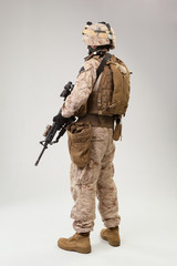 Soldier in US marines uniform with rifle on light grey background, studio shot