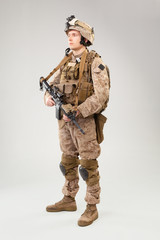 Soldier in US marines uniform with rifle on light grey background, studio shot