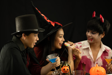 Asian young people attend a Halloween party which is dressed like zombies, devils, witches and drinking wine on Halloween fun.