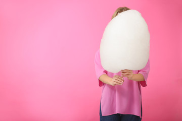 Young woman with tasty cotton candy on color background