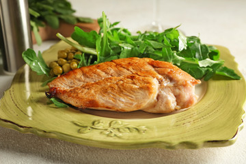 Plate with tasty arugula salad and chicken on table