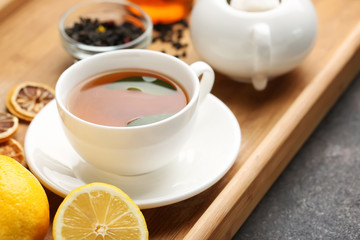 Tray with cup of hot tea on table