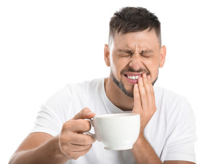 Man with sensitive teeth and cup of hot coffee on white background