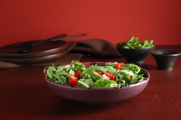 Plate with tasty arugula salad on table