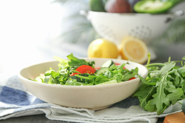 Bowl with tasty arugula salad on table