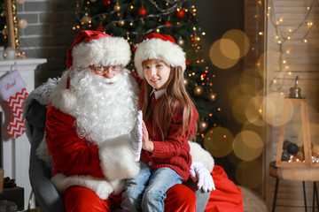 Fototapeta na wymiar Santa Claus and little girl in room decorated for Christmas