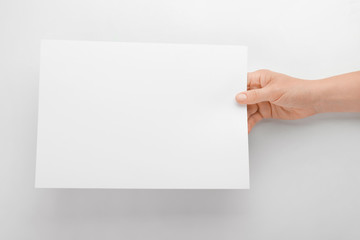 Obraz premium Female hand with empty sheet of paper on white background