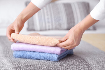 Female housekeeper putting clean towels on bed