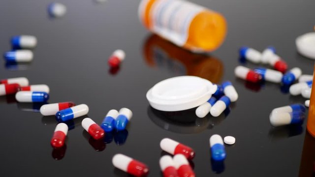 Prescription drug antibiotics falling down in slow motion with pill bottles among the medicine capsules.