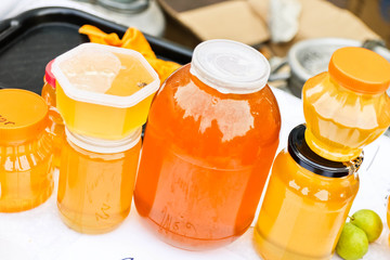 Homemade honey in glass jars on a craft market stall.