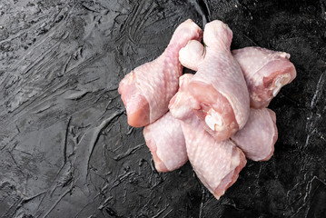 Raw chicken legs on black background.