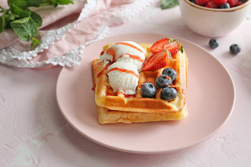 Plate with tasty sweet waffles, ice cream and berries on table
