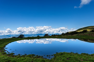 Fototapeta na wymiar Small lake with reflections with sky and clouds, Monte Baldo, Italian Alps near Verona and lake Garda, Veneto, Italy, south Europe