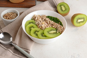 Bowl with tasty oat flakes and kiwi on white table