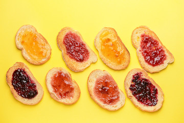 Fototapeta na wymiar Tasty toasted bread with different jams on color background