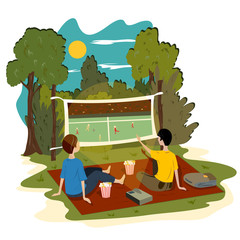 Young guys sit in the park outdoors and watch a football match on the projector.
