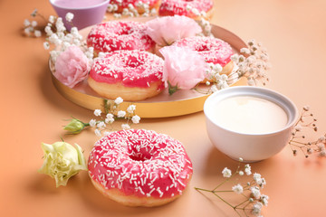 Composition with sweet tasty donuts and flowers on color background