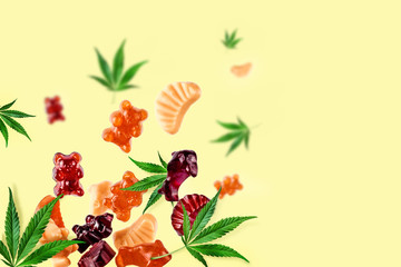 Colored gummies fly along with cannabis leaves. Chewing candies with CBD oil, THC. Creative...