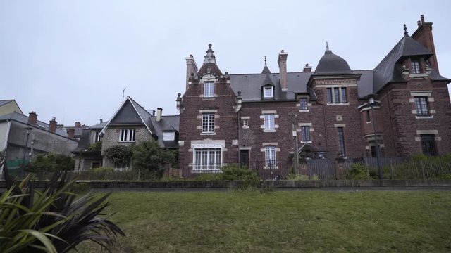Old dark manor on background of cloudy sky. Action. Large country house in gothic style of dark brick brings fear in cloudy weather