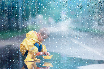 a boy plays boats in a puddle / childhood, walk, autumn game in the park, a child on a walk