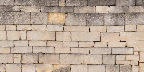 detail of an old city wall made of many different stones in Bordeaux France in web banner template header panorama