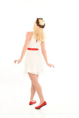 full length portrait of blonde girl wearing a white dress and flower crown.  Standing pose, isolated against a  white studio background.
