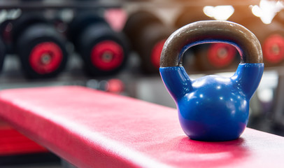 Naklejka na ściany i meble Sport equipment in gym concept .Blue kettlebells on red chair in modern sport gym and fitness.Workout lifestyle .