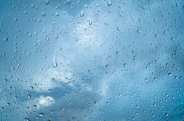 Fresh water drops after raining on blue glass window background in car.
