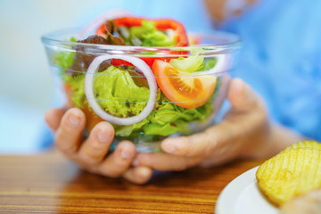 Asian senior or elderly old lady woman patient eating breakfast healthy food with hope and happy while sitting and hungry on bed in hospital.