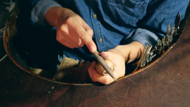 Male silversmith is burning the frame of the silver ring. A ring is getting polished by the silversmith