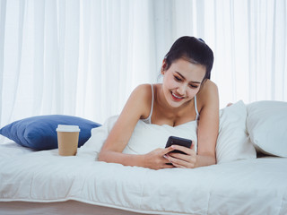Beautiful looking women are playing the phone on the bed,girl resting with coffee at home on holiday
