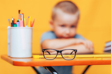 boy sitting ubfocused glasses in focus. Concept problem of ophthalmology correction of myopia. back to school. Selective focus. upset child