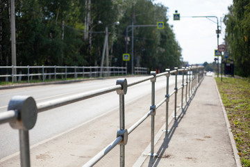 The barrier from the road. The fence along the highway. Metal fence for pedestrian safety.