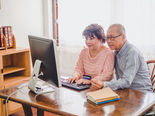 elder couple using computer together with credit card at home